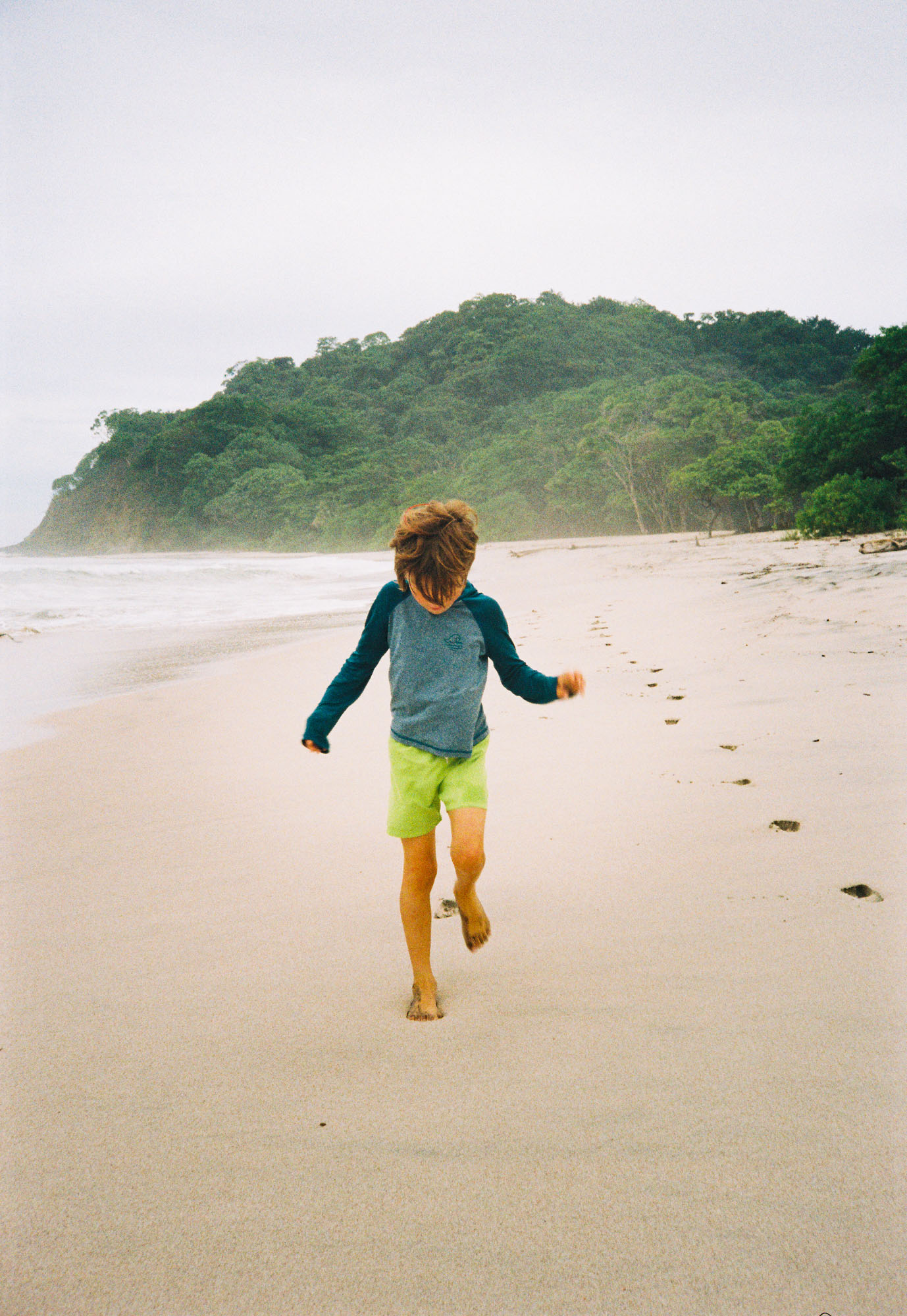 Child running barefoot along the white sand at Playa Barrigona
