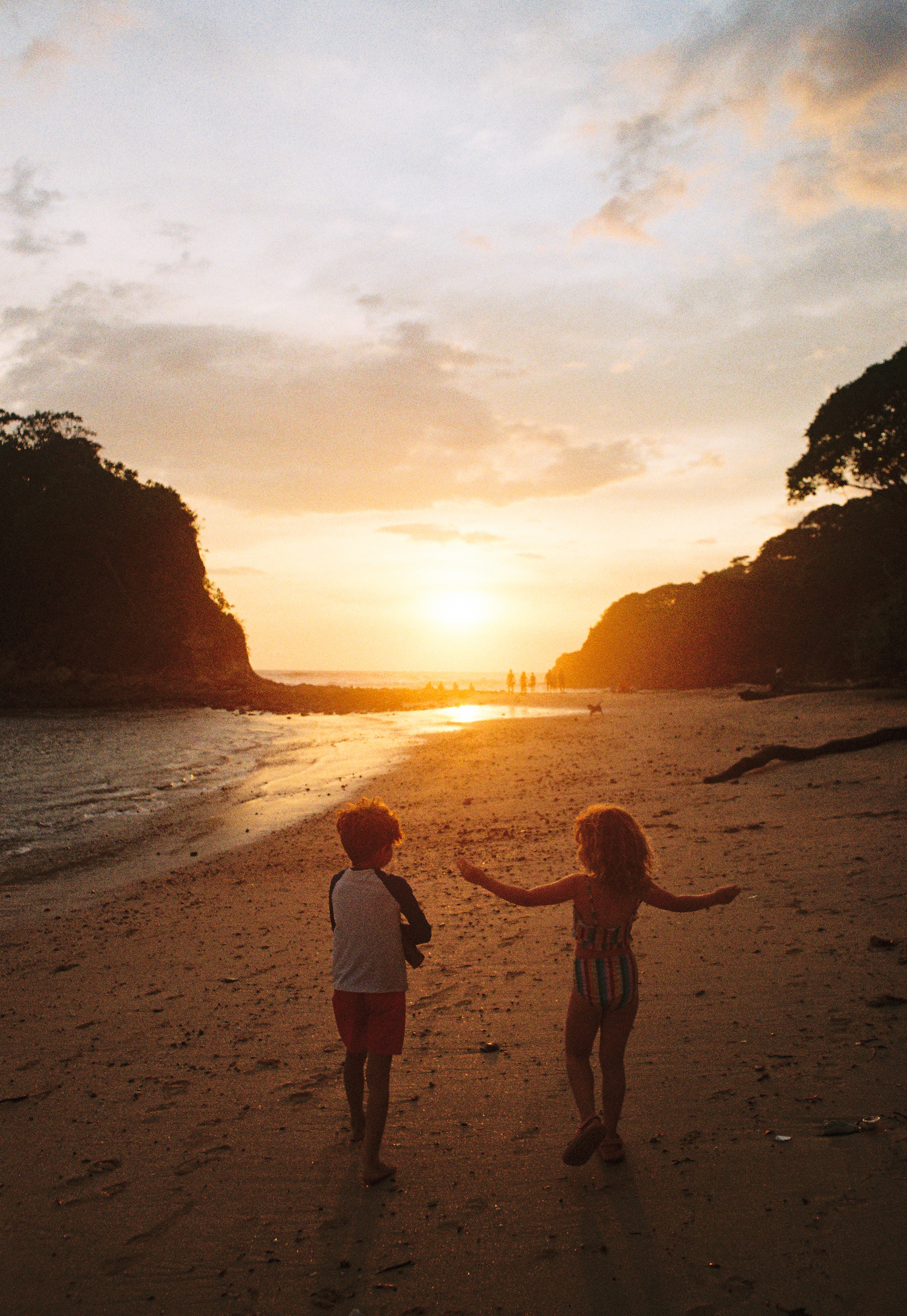 Two kids walking on the beach at sunset in Nosara
