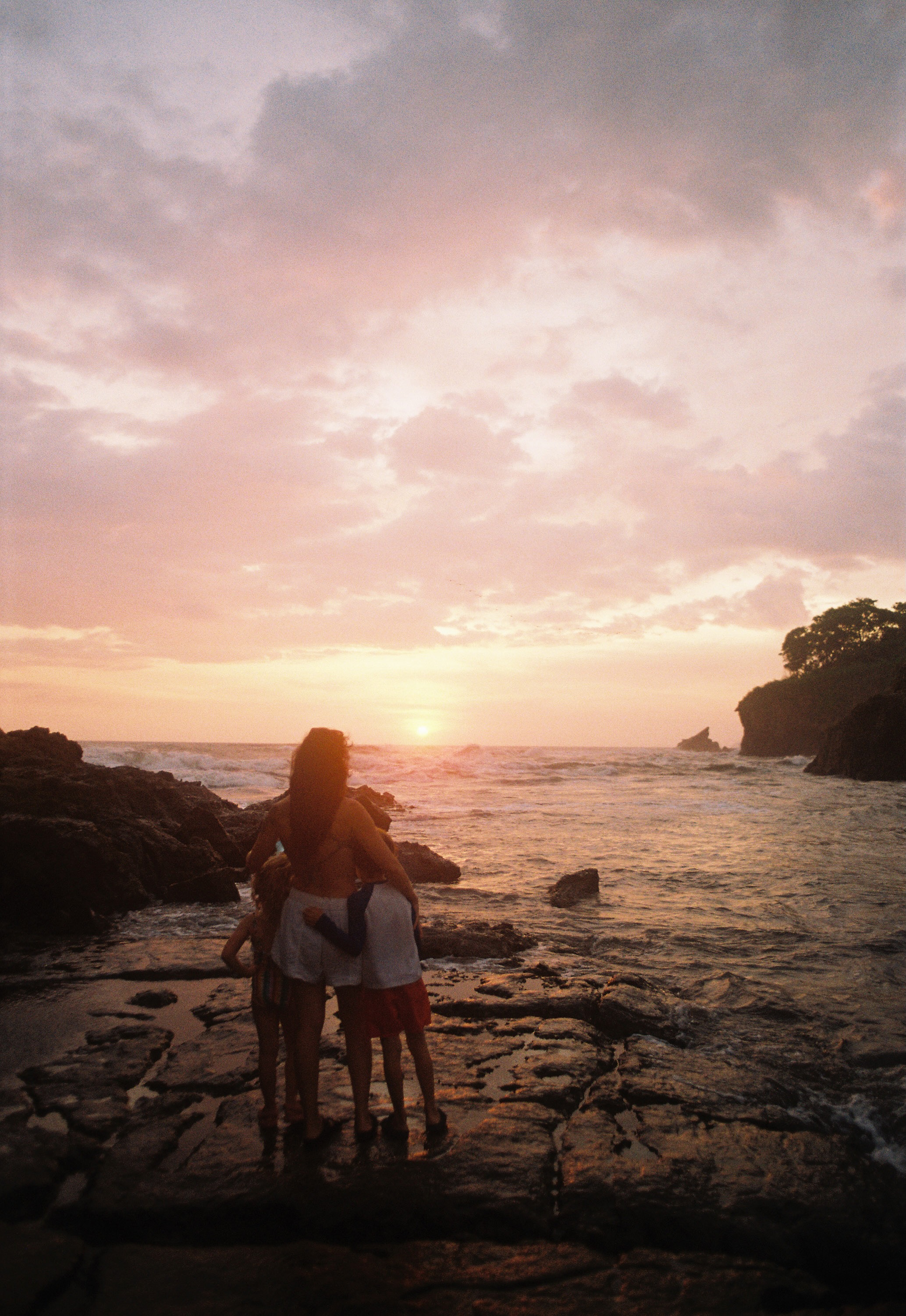 Family watching the sunset together from the rocks on the coast of Nosara