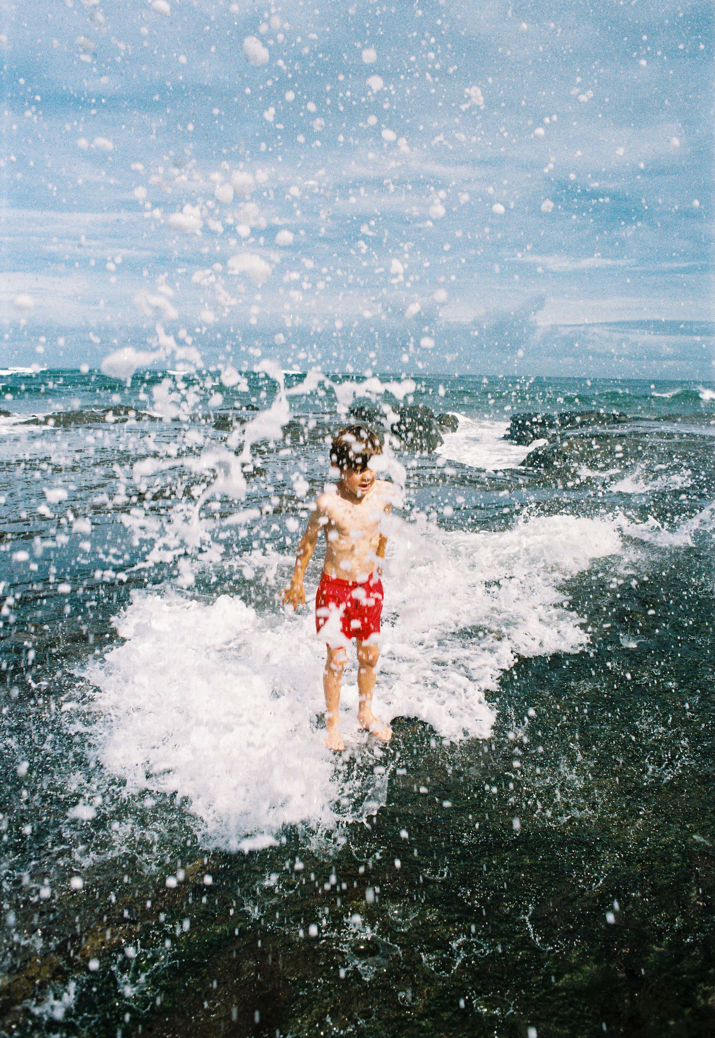 Kid playing in the ocean waves at Playa Pelada in Nosara