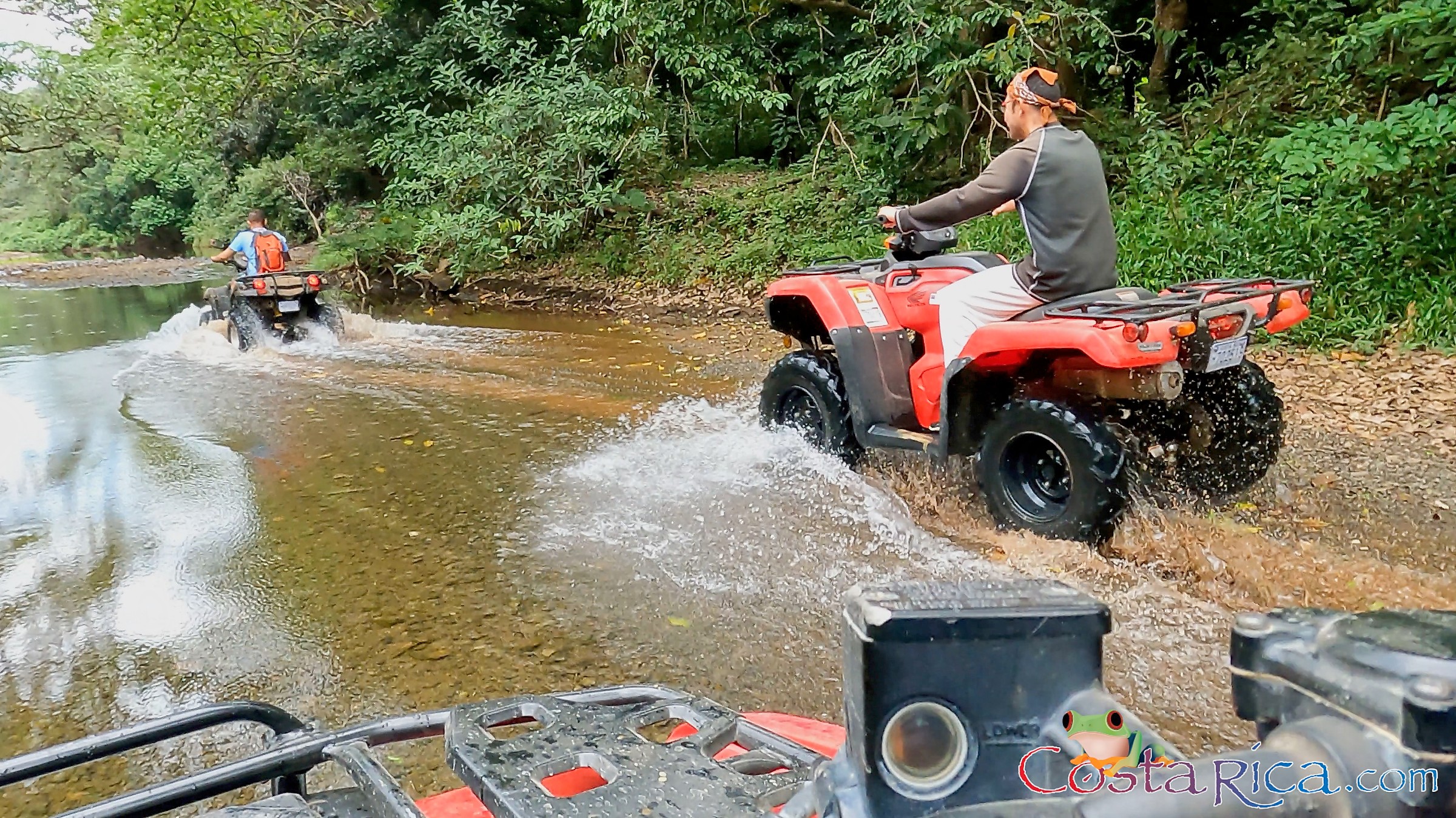 ATV riders splashing through a jungle river crossing in Nosara, Costa Rica