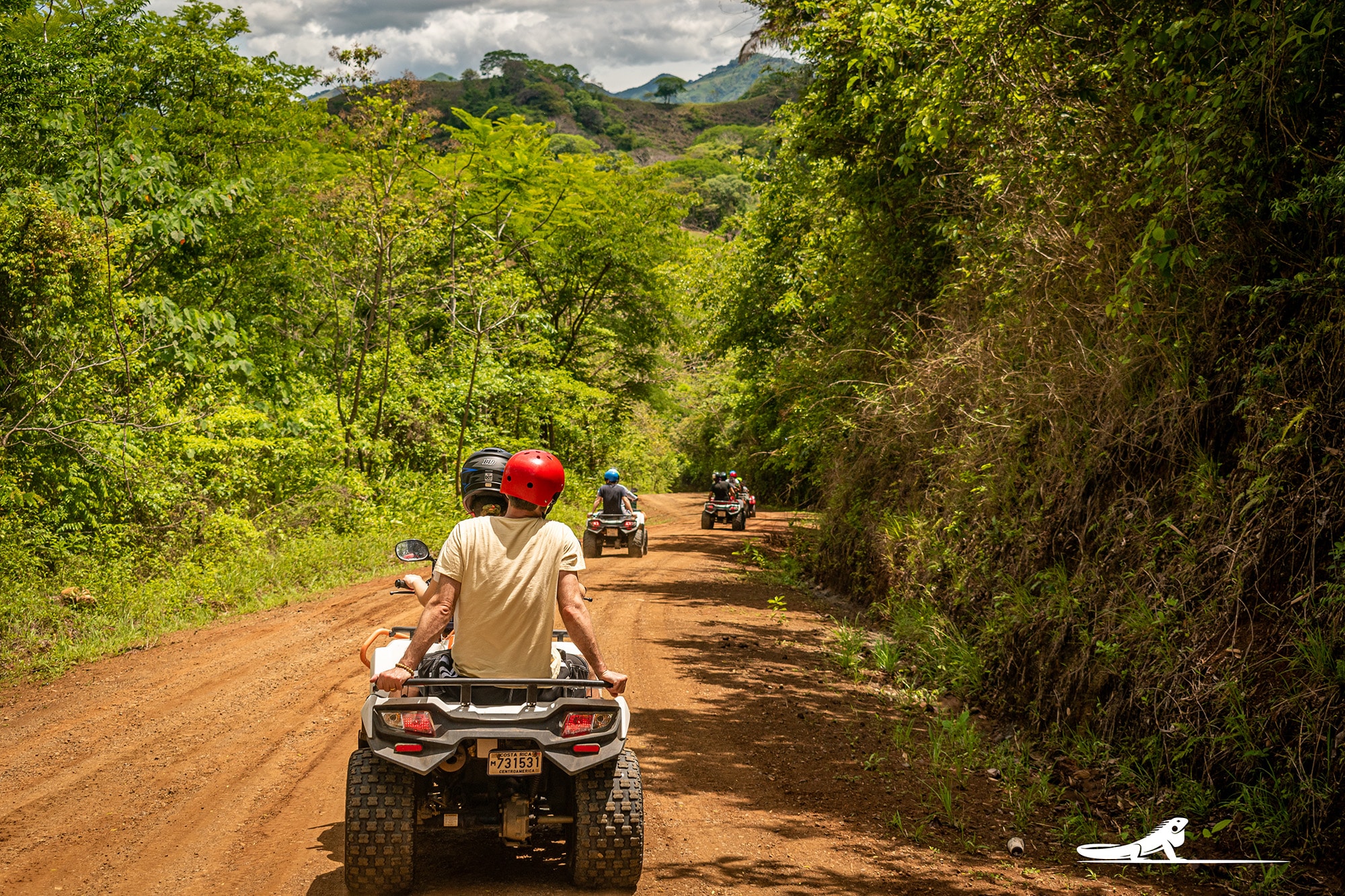 ATVs riding down a red dirt jungle trail in Nosara, Costa Rica