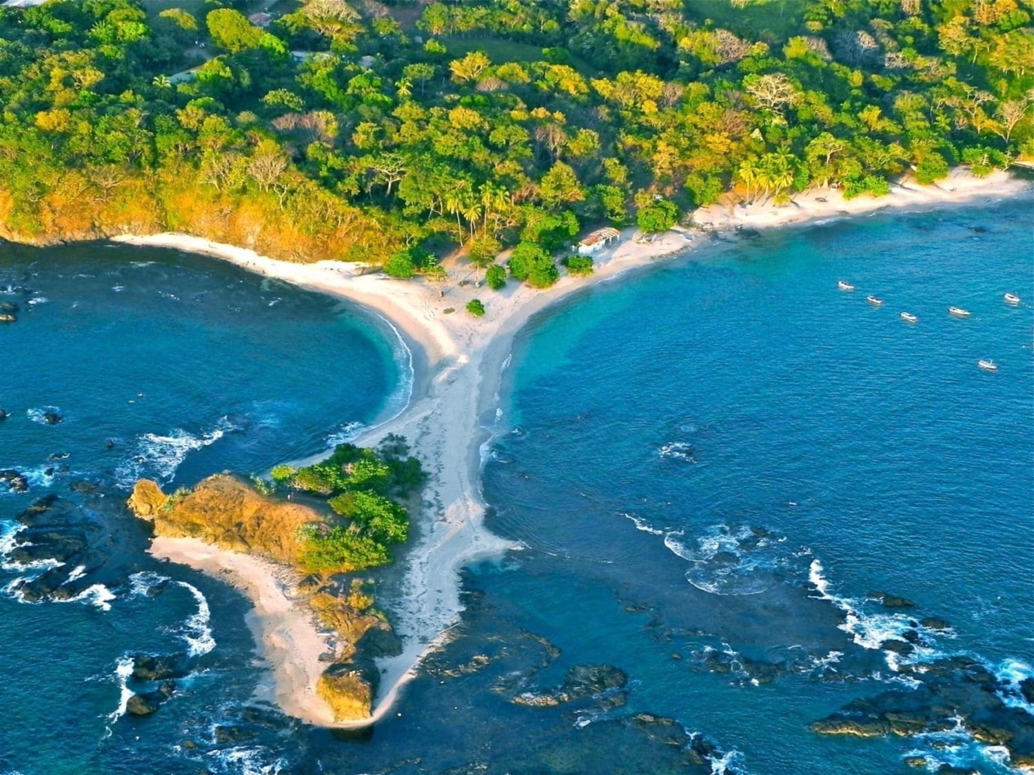 Aerial view of San Juanillo's whale tail beach formation in Costa Rica, with turquoise water on both sides of a sandy peninsula