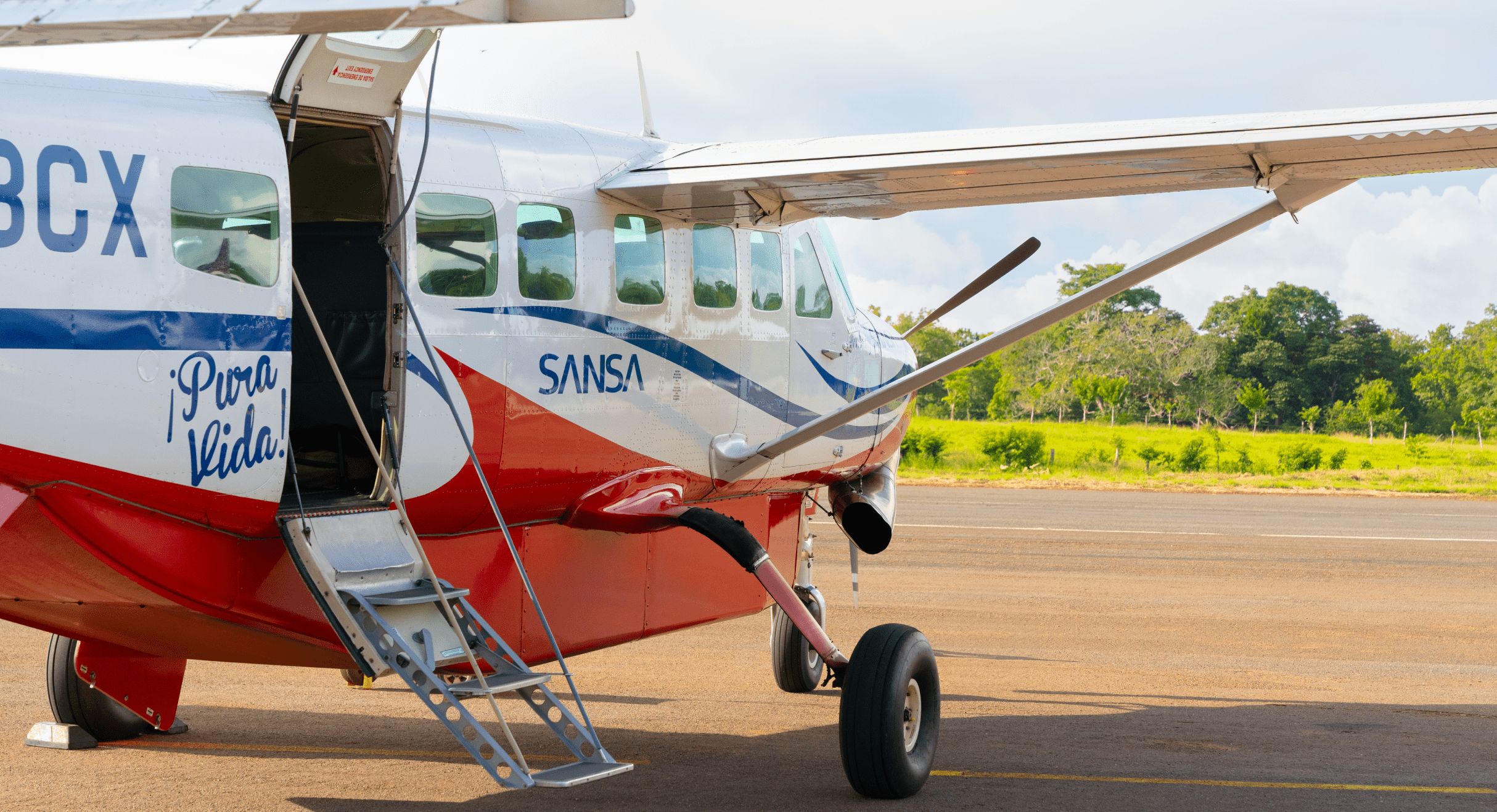 Sansa Airlines Cessna Grand Caravan with door open on a jungle airstrip