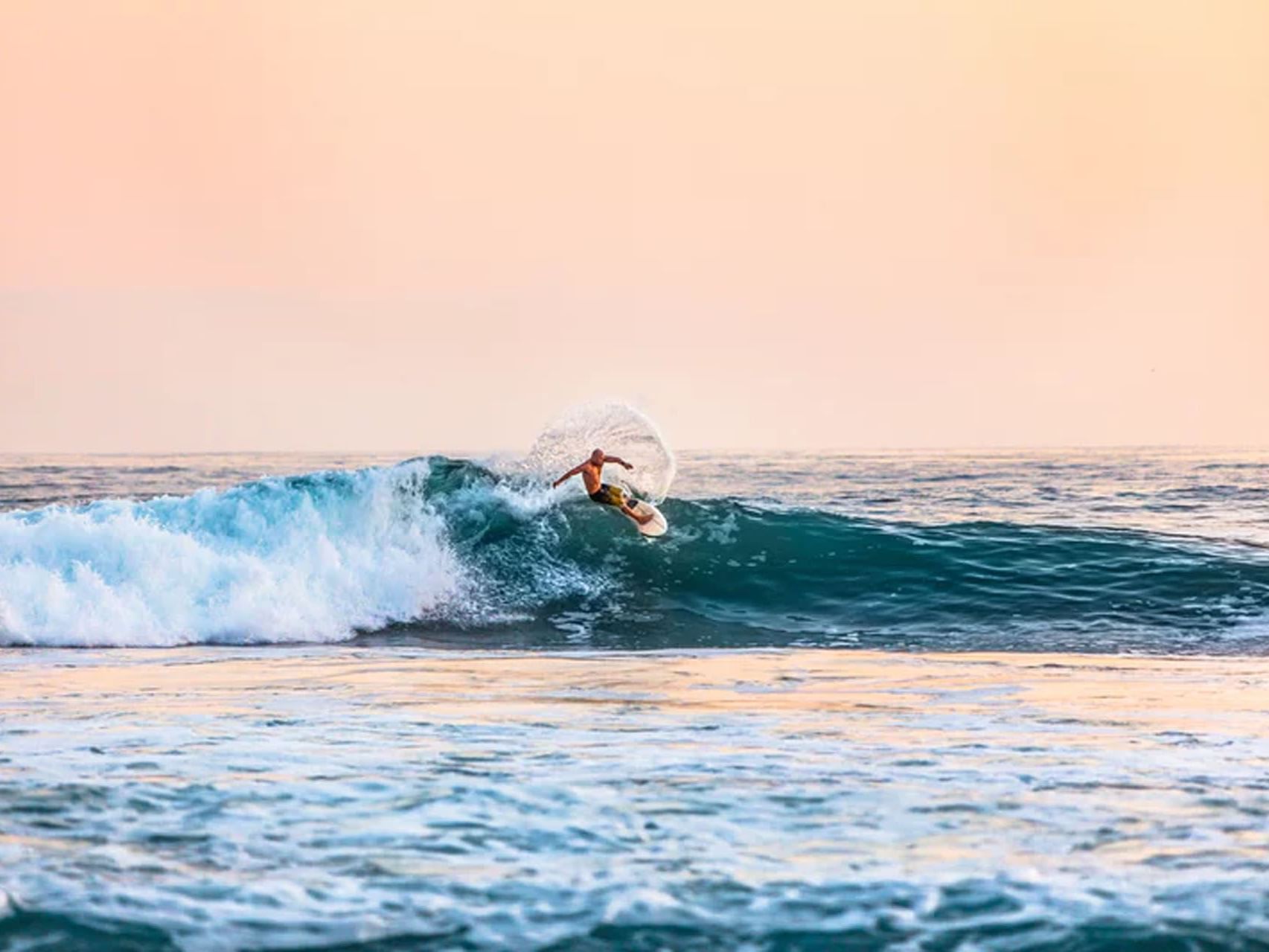 Surfer catching a wave at golden hour at Playa Guiones