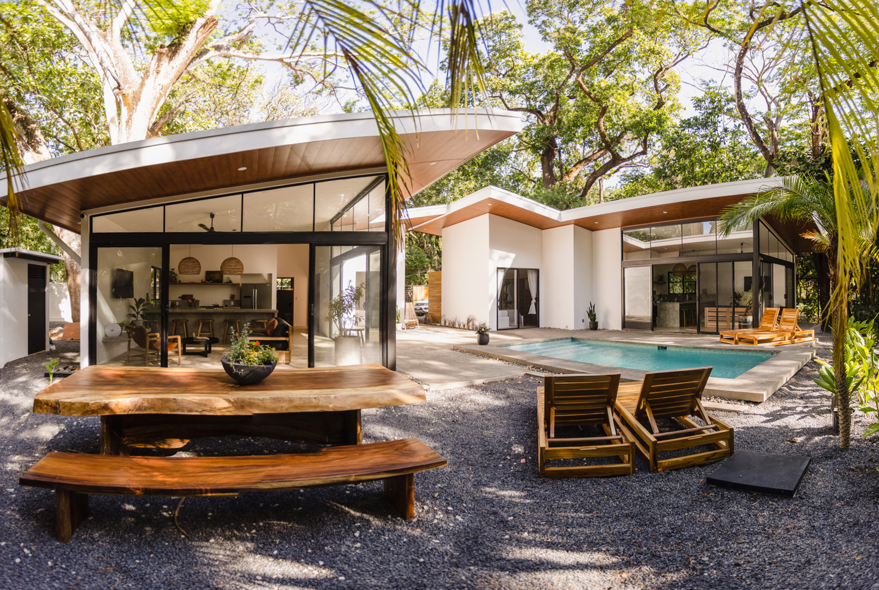 Panoramic view of both Kembar homes with pool and live-edge wood table